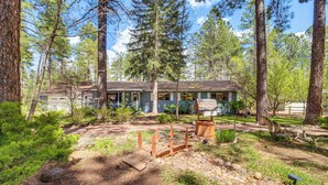 Un chalet rustique entouré de grands arbres et doté d’une terrasse en bois.