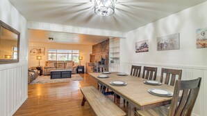 Un coin repas avec une table en bois dressée pour quatre personnes, entourée de chaises en bois.