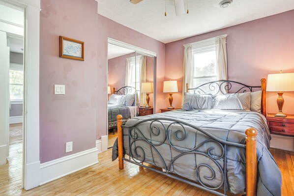 A bedroom with a bed, two bedside tables, a mirror, and a window.