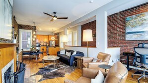 A spacious living area with a fireplace, leather sofas, a dining table, and a kitchen in the background. - Loft in the Heart of Dtwn Knoxville (Knoxville)