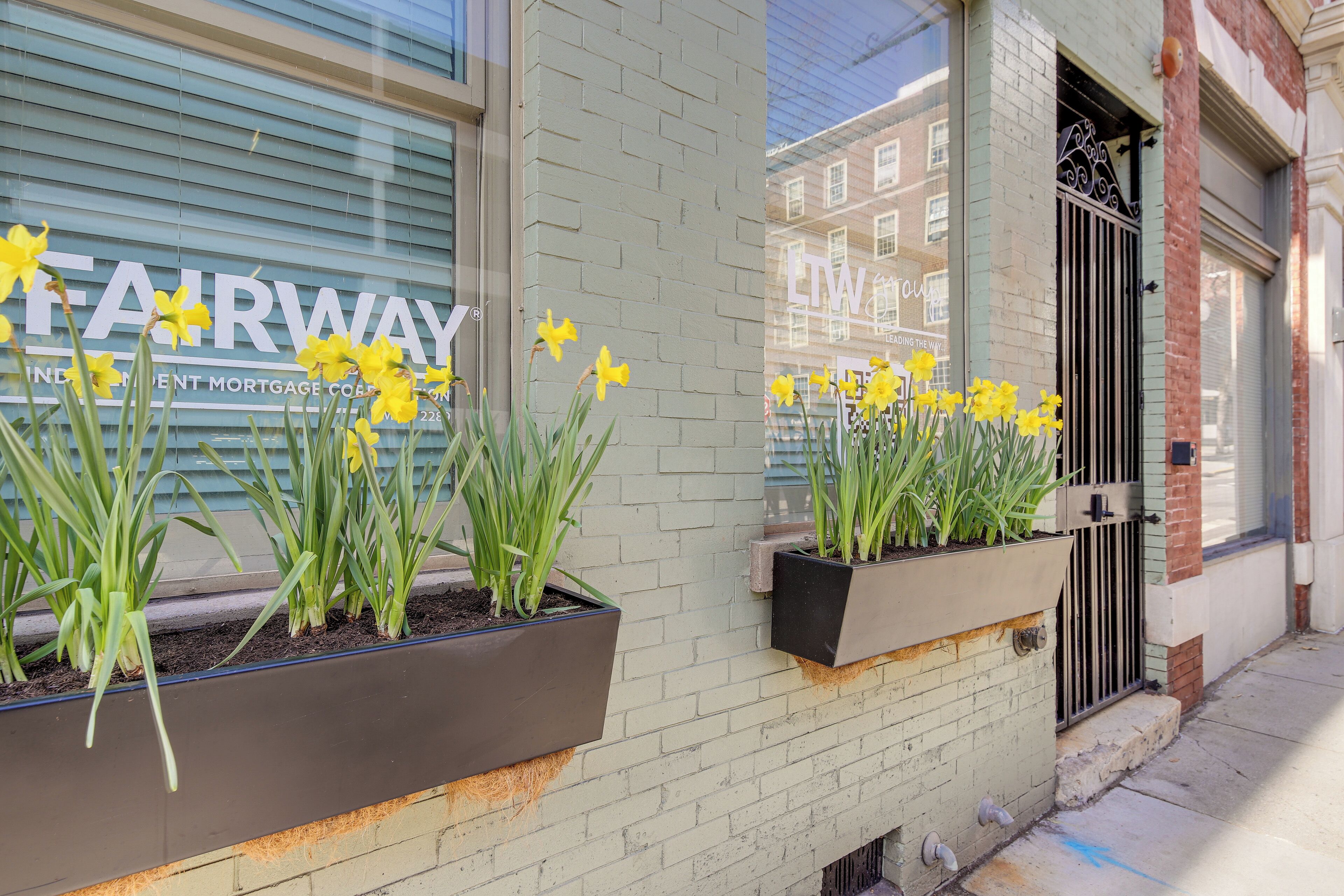 A building with a brick facade, a window with the text "FAIRWAY INDEPENDENT MORTGAGE CO." and a door with a metal gate.