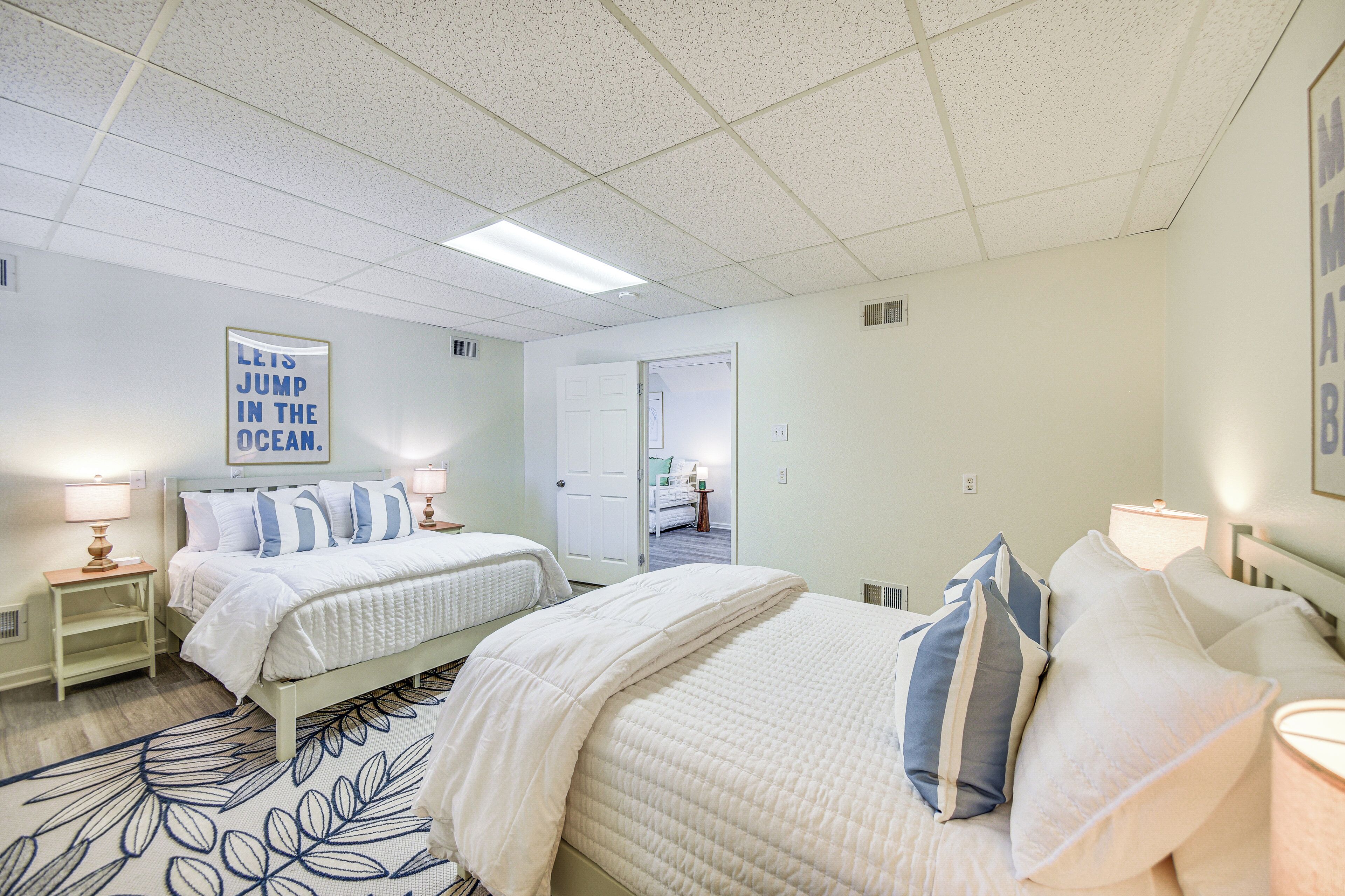 A hotel room with two beds, a large window, and a door leading to a bathroom.