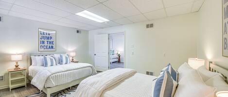 A hotel room with two beds, a large window, and a door leading to a bathroom.