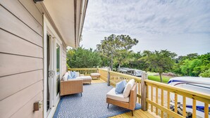 A covered deck with wicker furniture and a blue patterned rug.