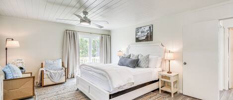 A bedroom with a bed, bedside tables, a ceiling fan, and a window with curtains.