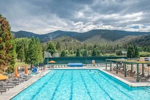 A swimming pool with lounge chairs and umbrellas, surrounded by a fence, with mountains in the background. - Pine Mountain Club Cabin w/ A/C & EV Charger (Pine Mountain Club)