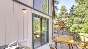 A deck with a table and chairs, a grill, and a sliding glass door leading to a deck with a view of trees. - Pine Mountain Club Cabin w/ A/C & EV Charger (Pine Mountain Club)