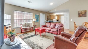 A spacious living room with a red leather sofa, a coffee table, and a dining area with wooden chairs.
