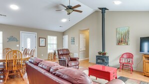 A spacious living room with a brown leather sofa, a red coffee table, and a fireplace.