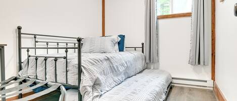 Una cama individual con estructura metálica y colchón con funda blanca y azul estampada.