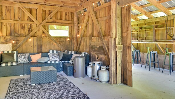 A rustic barn interior with a sofa set, gas cylinders, and metal stools. - Cozy Catskills Cabin - 12 Mi to Windham Mountain! (East Durham)