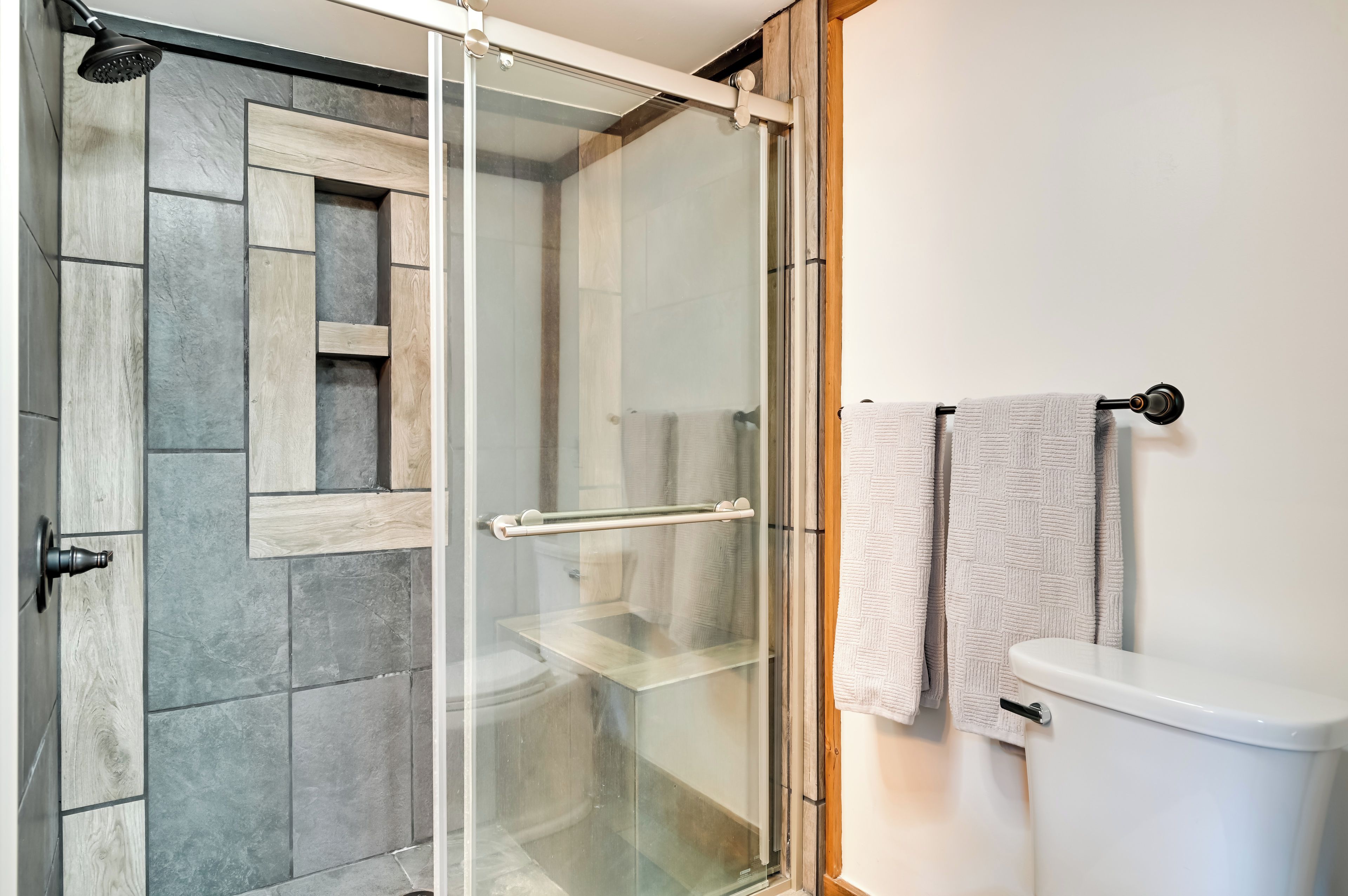 Un baño moderno con cabina de ducha de vidrio, inodoro y perchero para toallas.