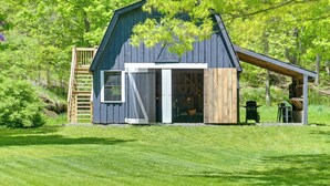 A rustic barn-style building with a large open door, a wooden ladder, and a covered porch area. - Cozy Catskills Cabin - 12 Mi to Windham Mountain! (East Durham)