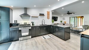 A modern kitchen with dark cabinets, a microwave, stove, and a hanging macrame wall decor. - Catskills Family Retreat: Fishing & Hiking On-site (East Durham)