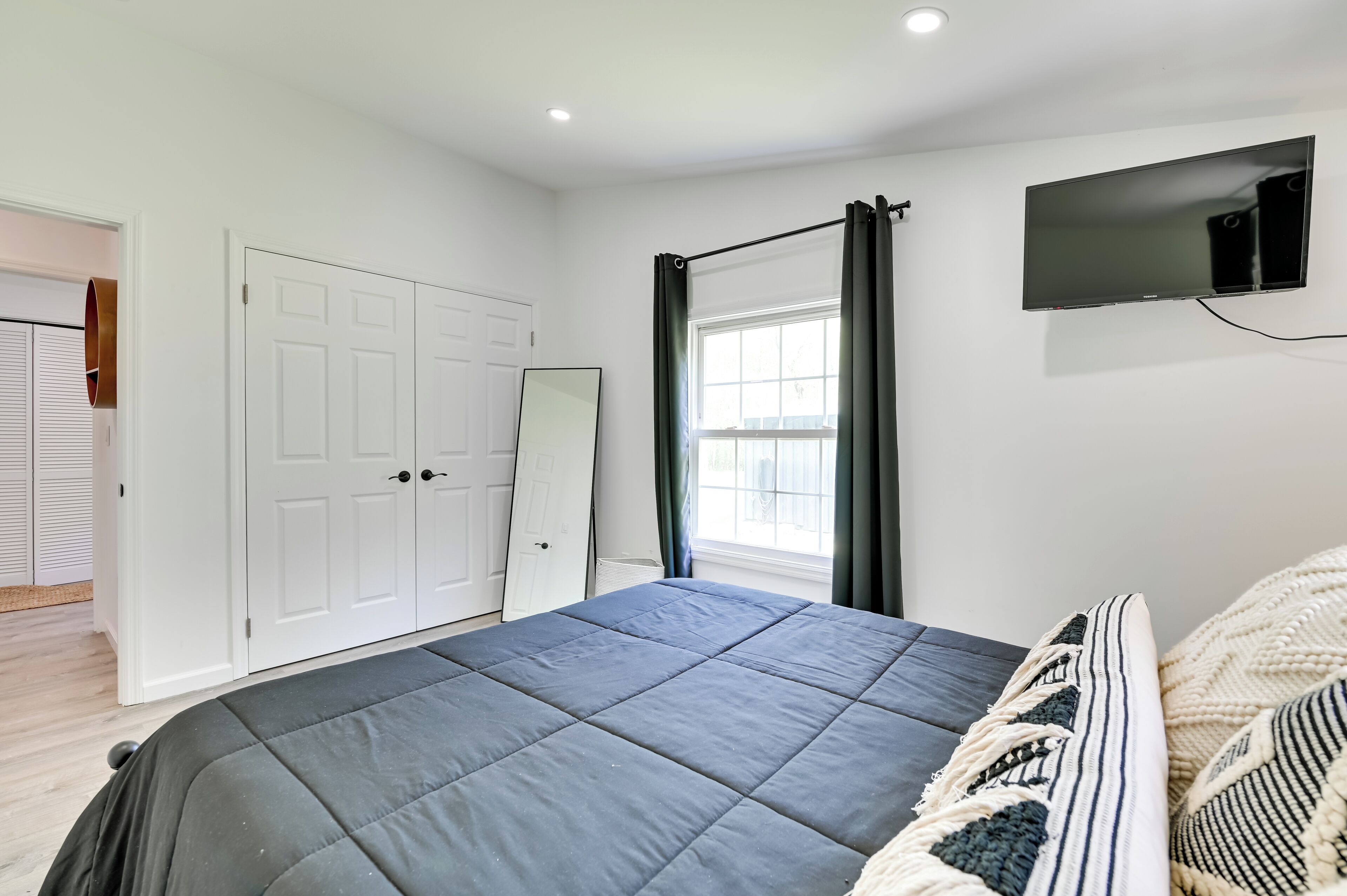 Une chambre à coucher avec un lit, une télévision, une fenêtre avec des rideaux et une porte.