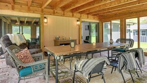 A covered patio area with a wooden ceiling, wicker furniture, and a dining table. - Catskills Family Retreat: Fishing & Hiking On-site (East Durham)