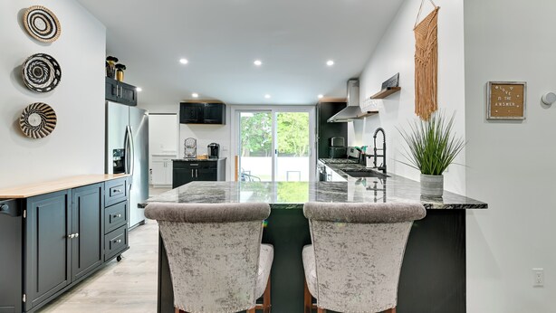 A modern kitchen with a central island, dark cabinetry, and a view to the outdoors. - Catskills Family Retreat: Fishing & Hiking On-site (East Durham)