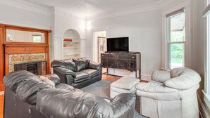 Een woonkamer met leren banken, een open haard, een televisie en een groot raam.