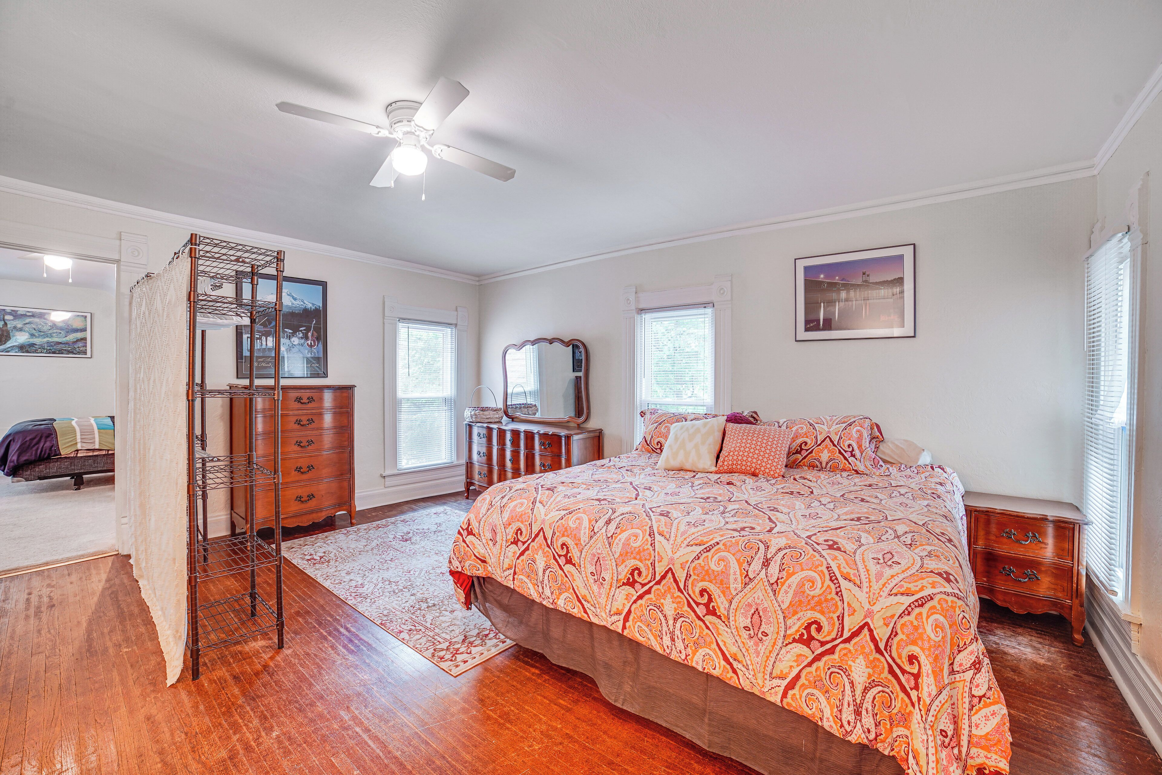 A bedroom with a large bed, wooden dresser, and a ceiling fan.