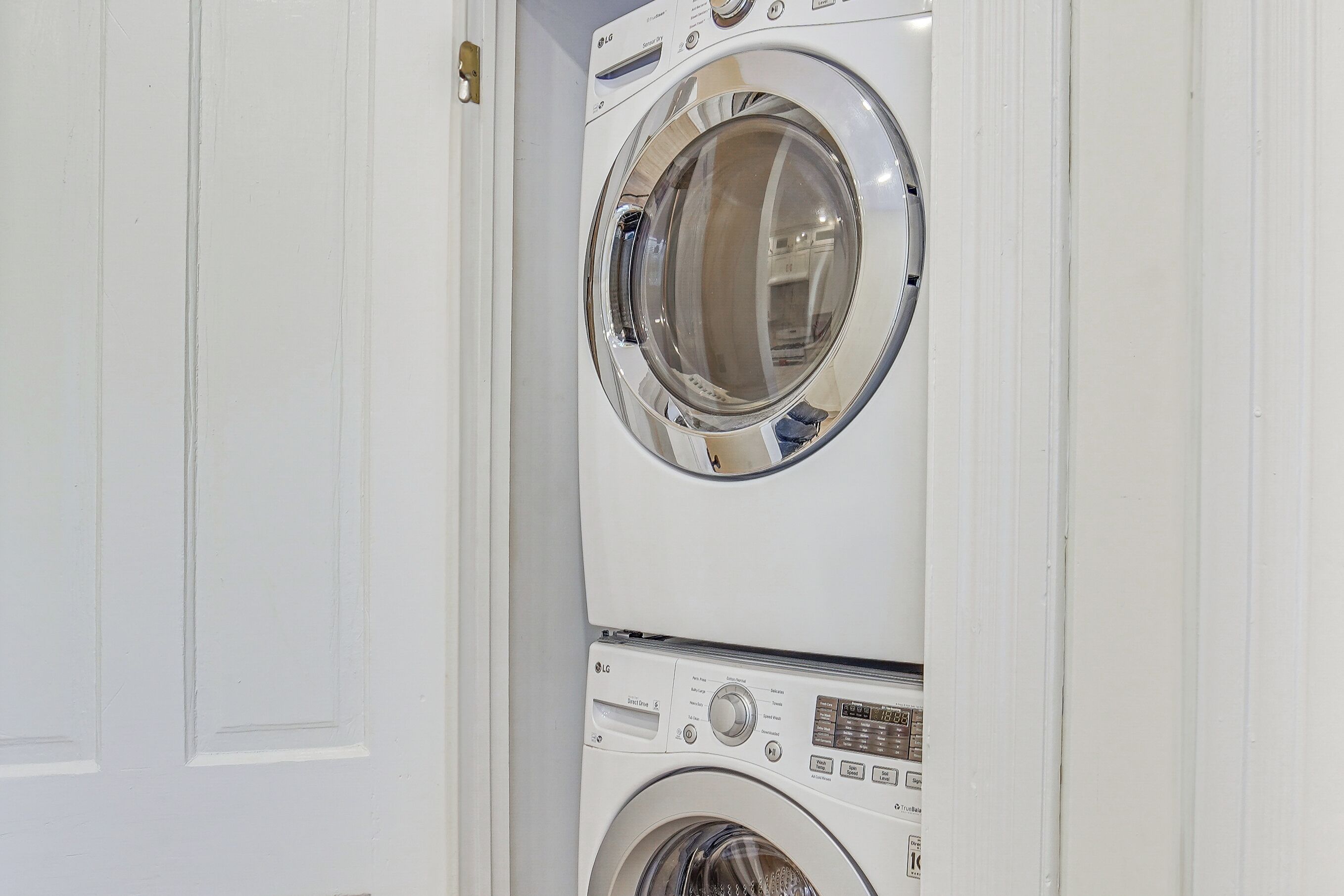 A stacked washer and dryer unit in a white-walled room.