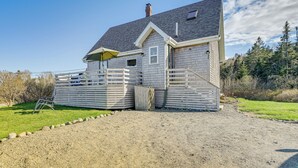 A two-story house with a fenced yard, a gravel driveway, and a wooden deck. - Peaceful Lubec Home w/ Views: Walk to Beach! (Lubec)