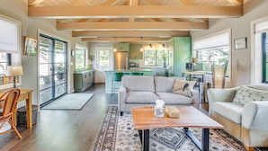 A spacious living area with a wooden ceiling, a sofa, a coffee table, and a view of the kitchen.