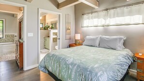 A bedroom with a large bed, a nightstand, a dresser, and a window with blinds.