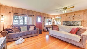 A wooden cabin interior with two sofas, a stone fireplace, and a ceiling fan. - Waterfront Grapeview Escape w/ Boat Dock & Views! (Grapeview)