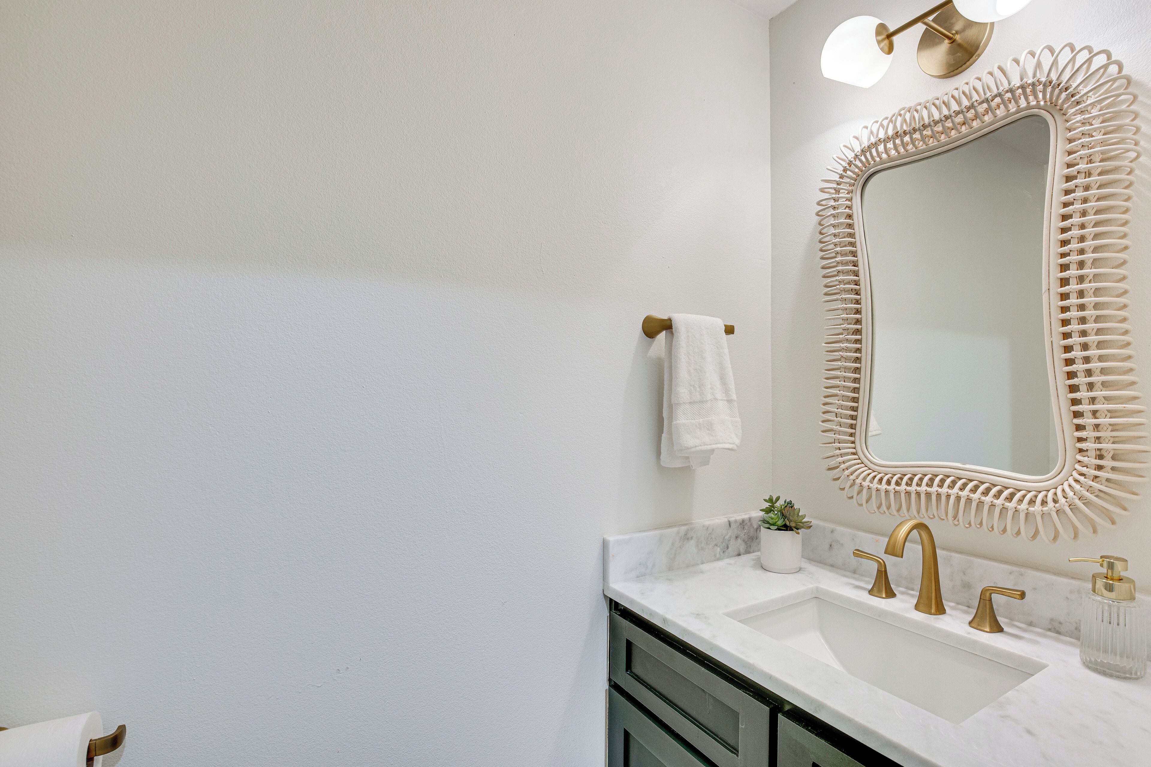 A bathroom with a white sink, gold faucets, and a decorative mirror frame.