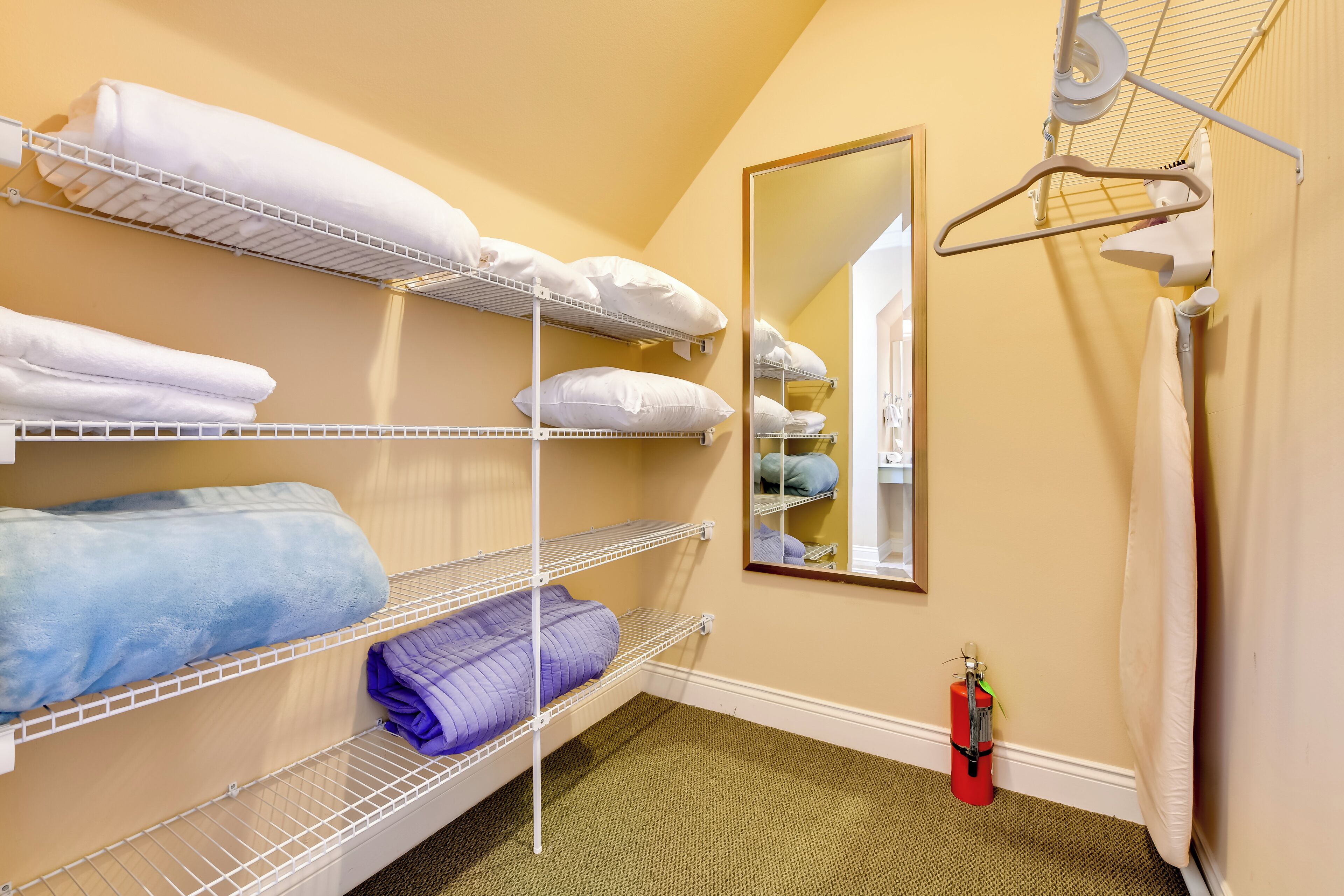 A hotel room with bunk beds, a mirror, a fire extinguisher, and a towel rack.