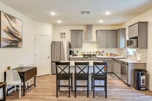 A modern kitchen with grey cabinets, stainless steel appliances, and a dining area with a table and chairs. - Spacious Family Home in Stockton - Pets Welcome! (Stockton)