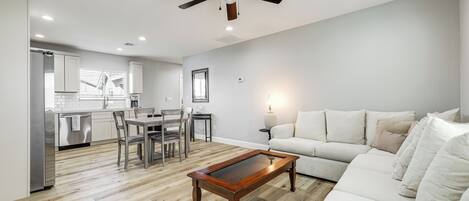 A modern living room with a wooden coffee table, a white sofa, and a ceiling fan.
