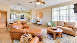 A spacious living room with a brown leather sofa, a wooden coffee table, and a ceiling fan.