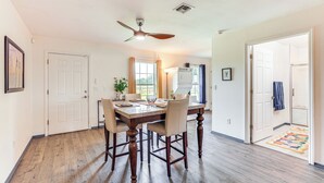 A dining area with a wooden table and chairs, a ceiling fan, and a view of the kitchen. - Idyllic Anthony Home: Riding Arena w/ Mirror Wall! (Anthony)