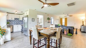 A modern kitchen with white cabinets, a stainless steel refrigerator, and a dining area with a wooden table and chairs. - Idyllic Anthony Home: Riding Arena w/ Mirror Wall! (Anthony)