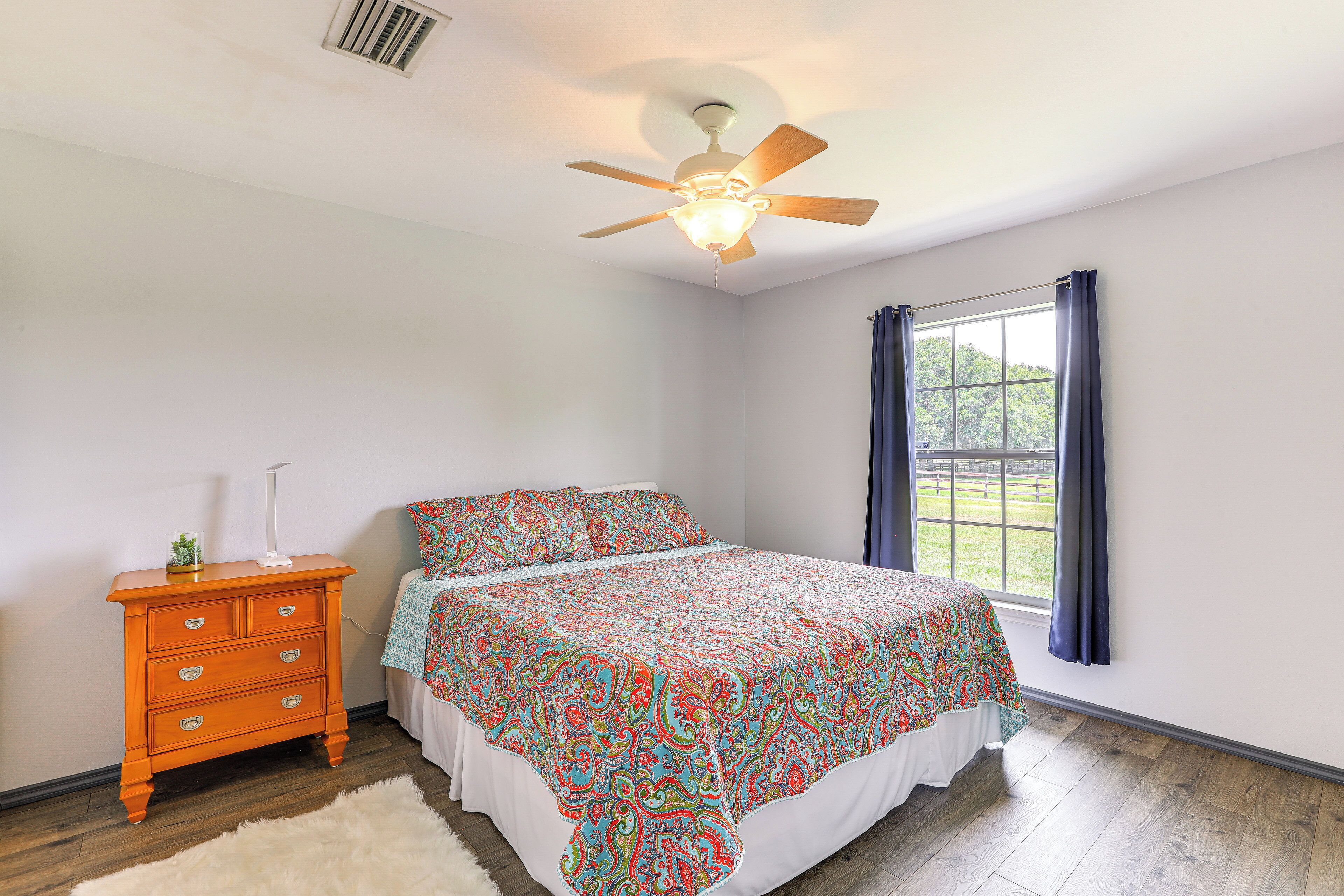 A bedroom with a bed, dresser, and window with curtains.