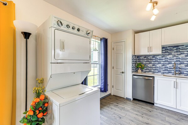 A laundry room with a washer and dryer, a sink, and a tiled backsplash.