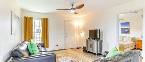 Un salon avec un canapé, un téléviseur et un ventilateur de plafond.