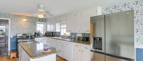 A modern kitchen with white cabinets, a stainless steel refrigerator, a microwave, and a dishwasher.