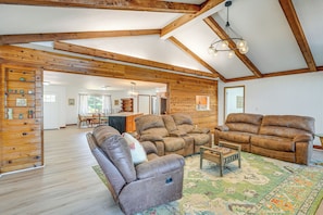 A spacious living room with wooden beams, a large sofa, a recliner, and a coffee table.