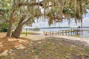A dock extending into a calm lake with a wooden structure on the far end, surrounded by trees with hanging moss.