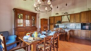 A spacious kitchen with wooden cabinets, a dining table set for four, and a chandelier. - Il Giardino, Pretaccione, Castelnuovo Berardenga, Siena and Chianti (Castelnuovo Berardenga)