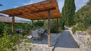 An outdoor patio with a wooden pergola, stone flooring, and a table set for dining. - Il Giardino, Pretaccione, Castelnuovo Berardenga, Siena and Chianti (Castelnuovo Berardenga)