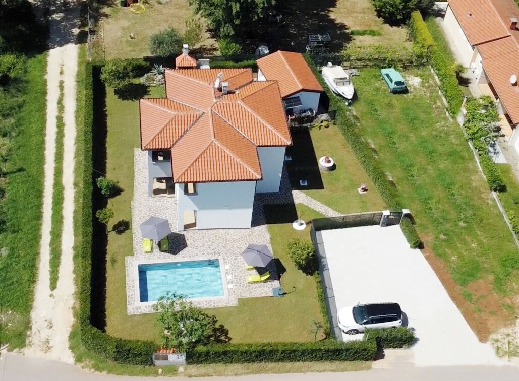 Luchtbeeld van een huis met zwembad, een overdekte patio en een garage.