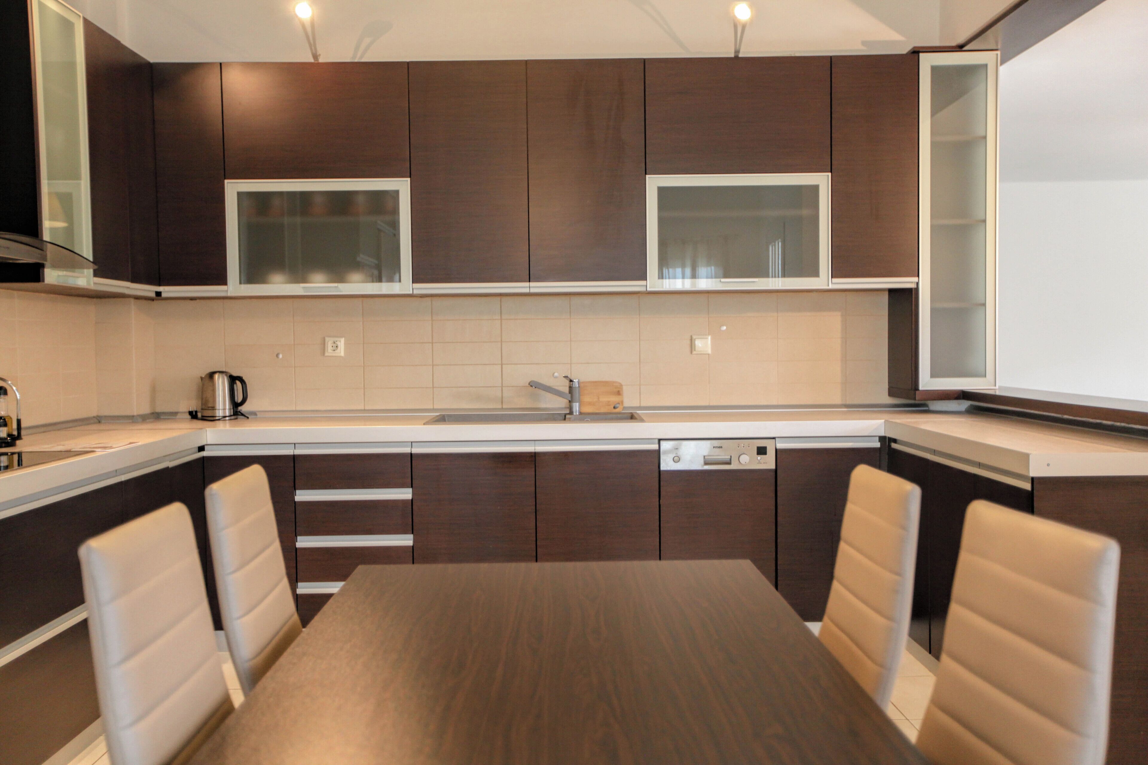 Una cocina moderna con armarios de madera oscura, un lavamanos de acero inoxidable y un lavavajillas integrado.