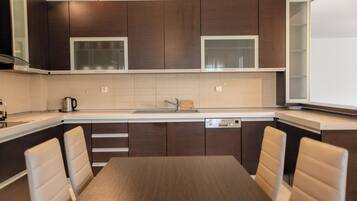 Una cocina moderna con armarios de madera oscura, un lavamanos de acero inoxidable y un lavavajillas integrado.