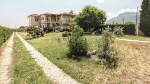 A two-story house with a paved driveway and a well-maintained lawn. - Meteora's Secret Garden House 2 (Kalabaka)