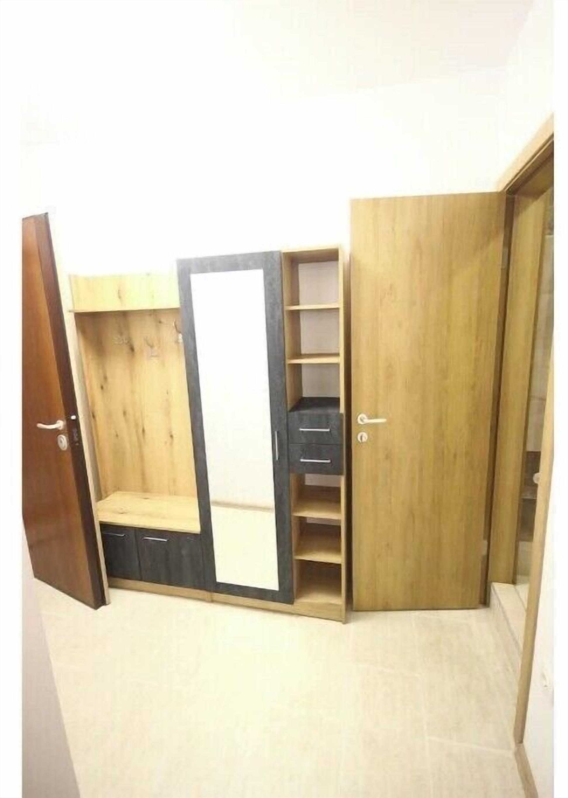 A room with a wardrobe featuring multiple compartments, including a hanging section and drawers.