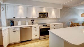 A modern kitchen with white cabinetry, a built-in microwave, and a stove.