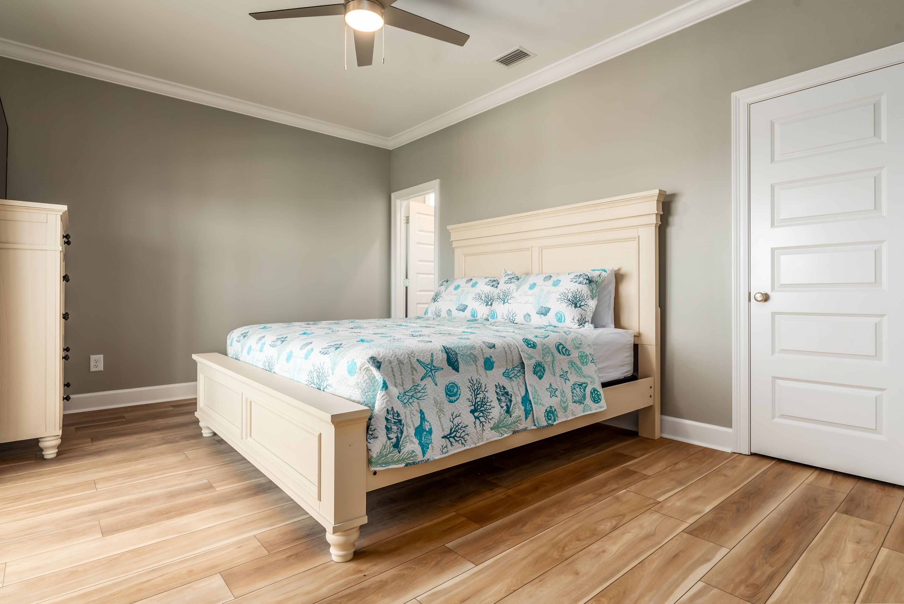 A bedroom with a bed, a ceiling fan, a wardrobe, and a door.